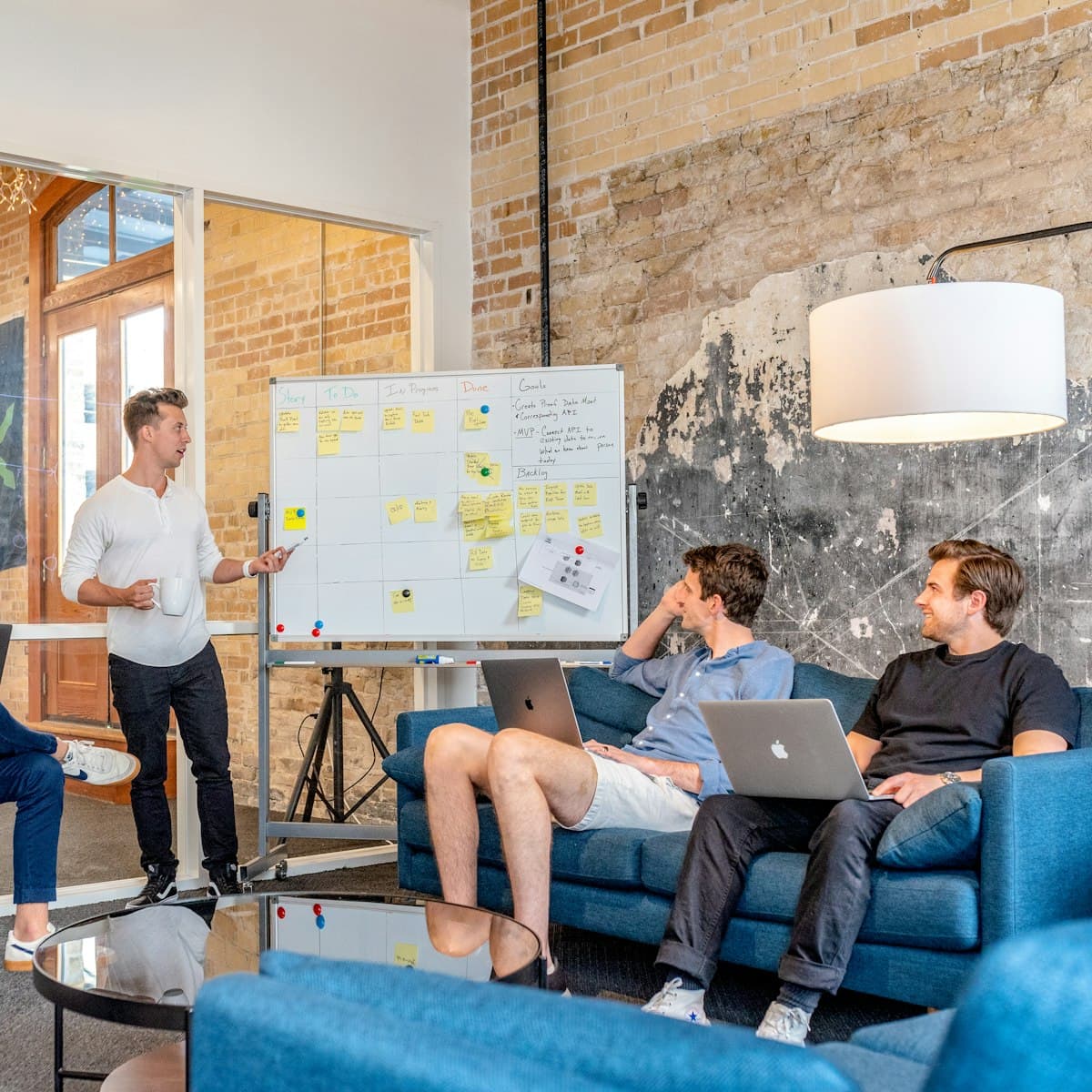 A small team brainstorming on sofas in front of a whiteboard