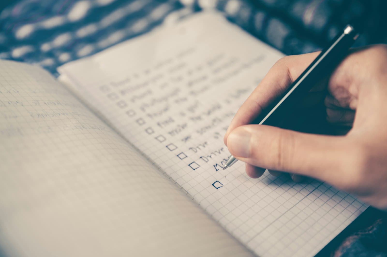 A hand ticking off items on a checklist in a notebook
