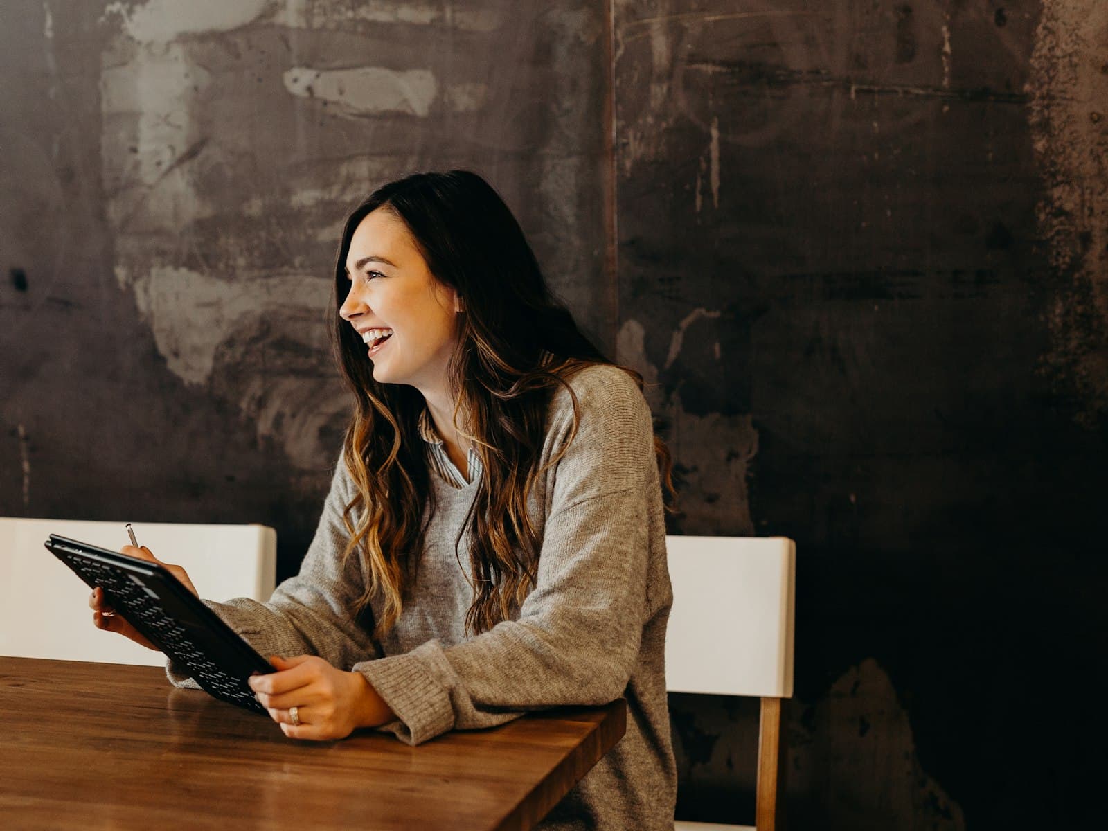 A professional smiling while reviewing work on a tablet at a wooden table